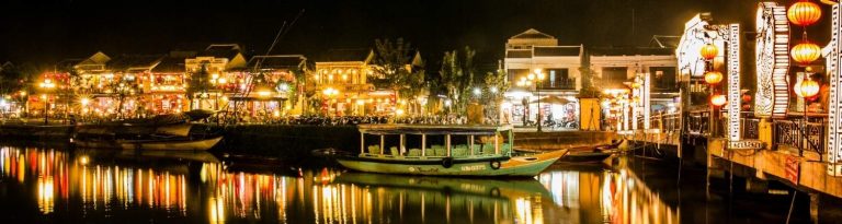 Buildings and boat on the water lit up at night in Vietnam