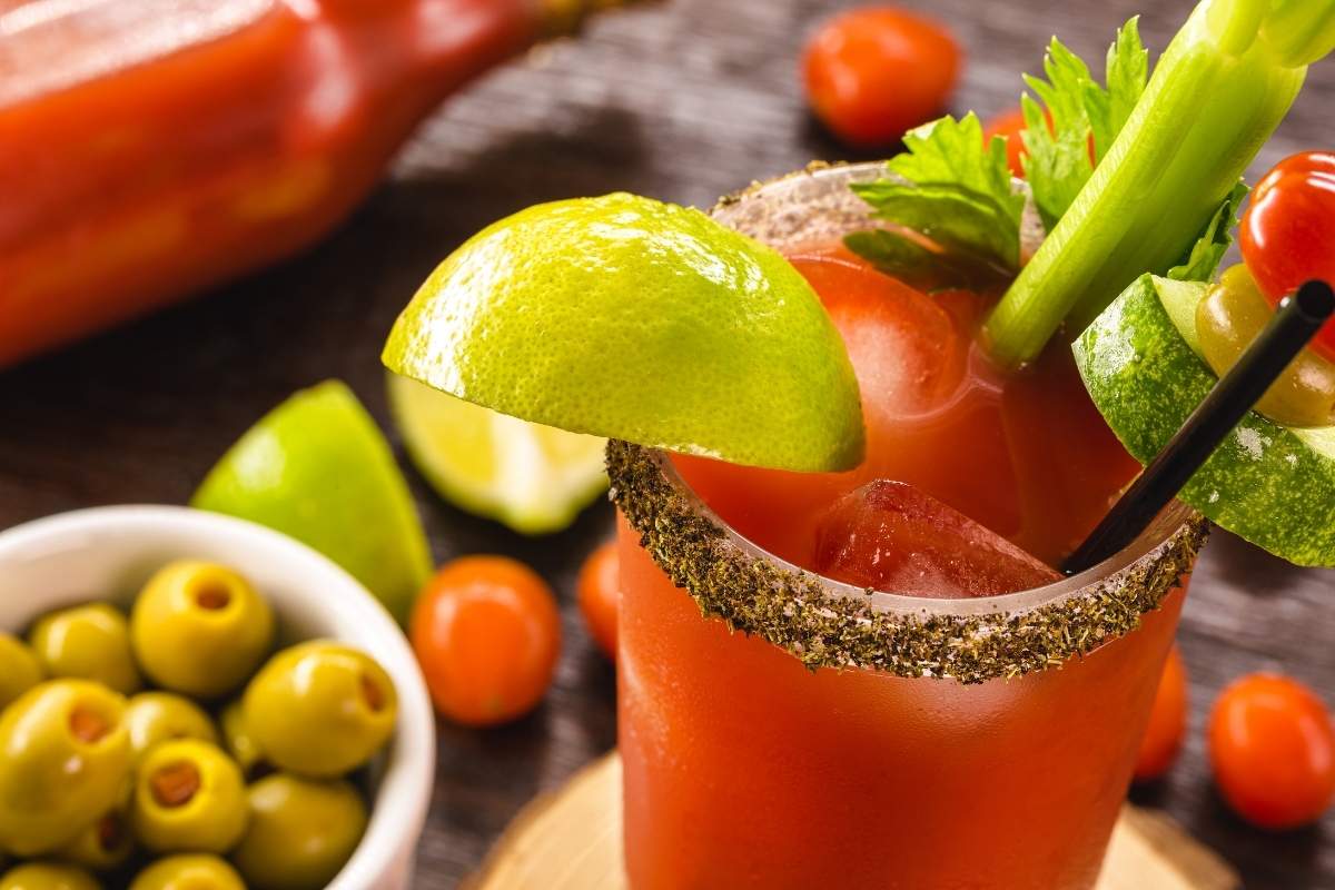Fun facts about Canada: Classic Canadian Caesar cocktail in a tall glass garnished with a salted rim, celery stick, and lime wedge.