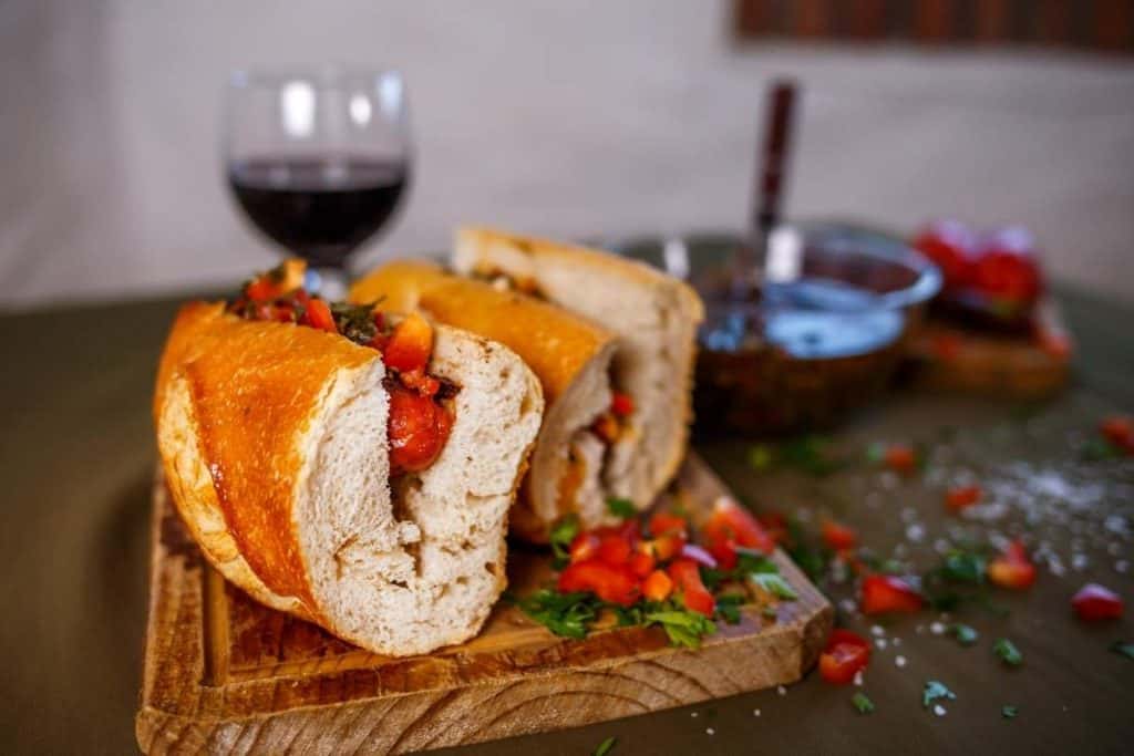 Close up shot of choripan, a popular street food in Argentina, on a wood plate with a glass of wine