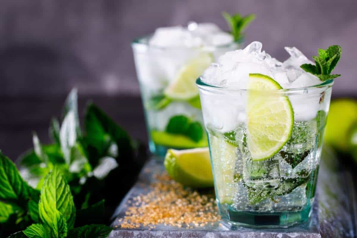 Two mojito cocktails with lime wedges and mint garnish