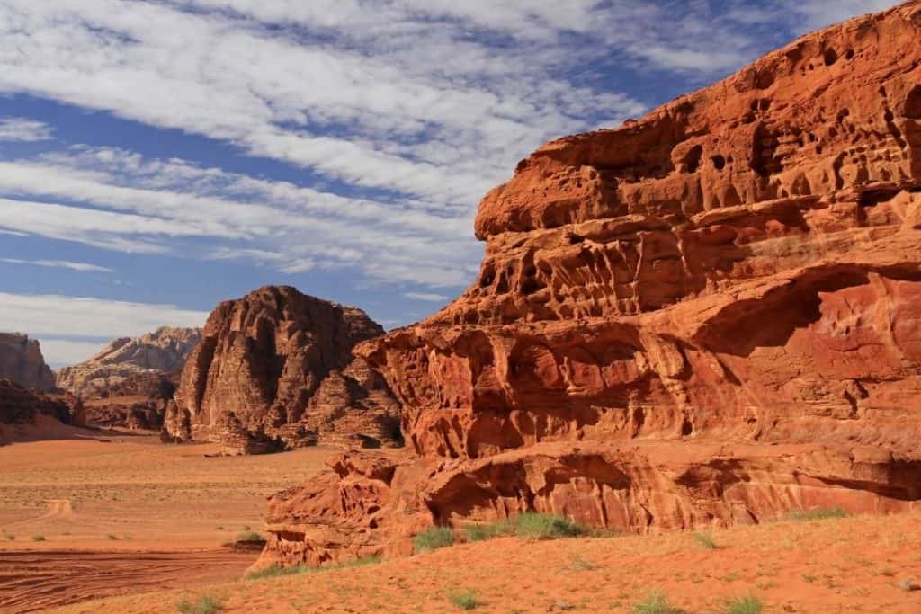 Red sand and cliffs in the Wadi Rum Desert, Jordan with a blue sky and white clouds
