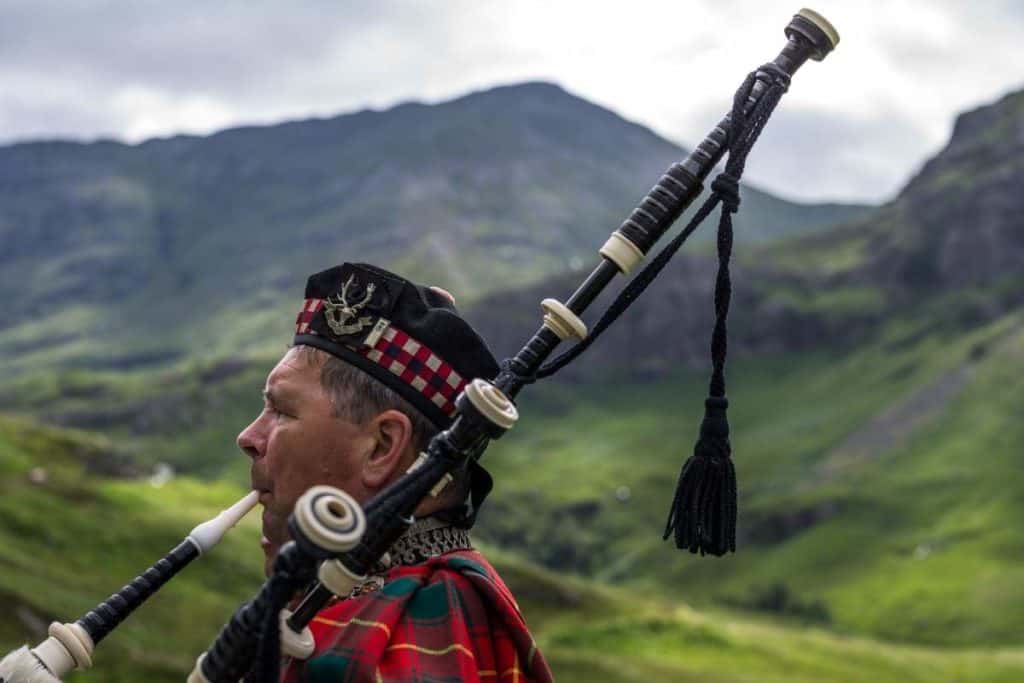 A bagpipe player performing outside on a cloudy day