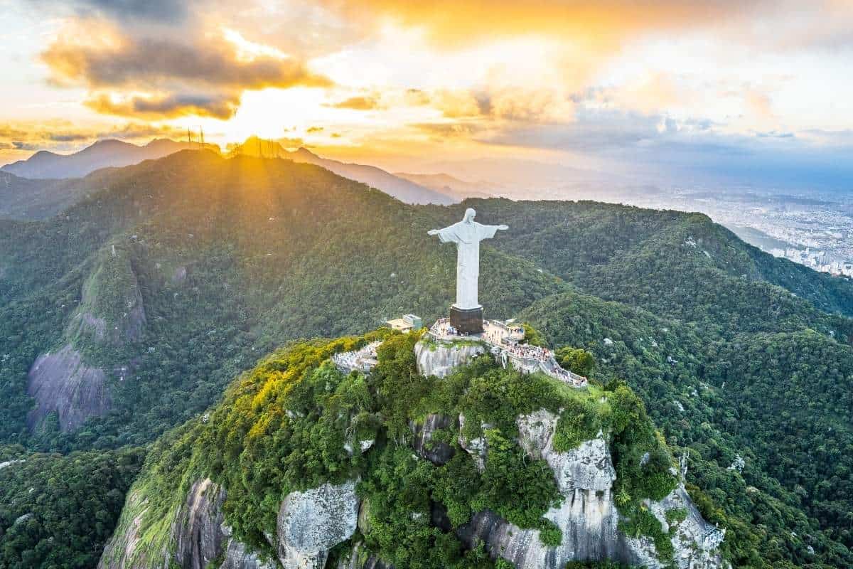 Aerial image of Christ the Redeemer, a statue sitting on top of a mountain overlooking the city of Rio de Janeiro, Brazil at sunset