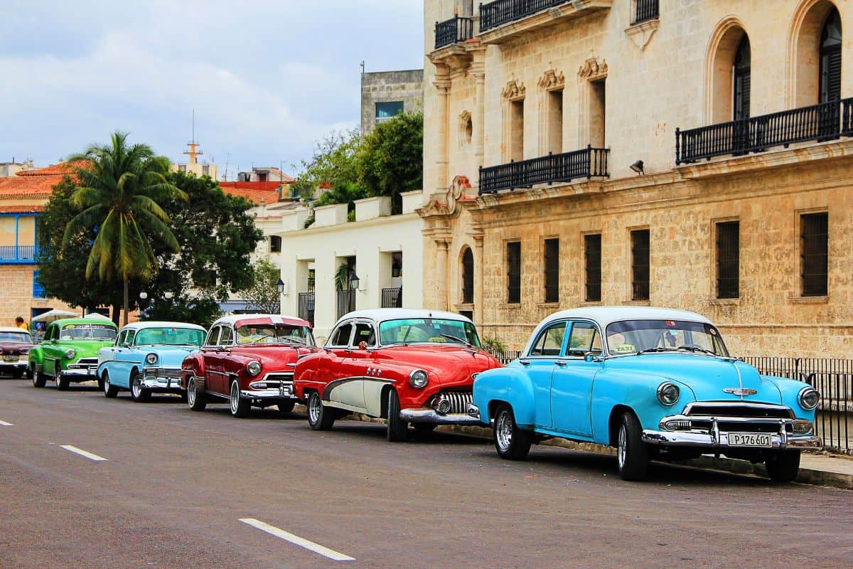 Lineup of colorful classic cars parked on the street in front of stone buildings in Havana, Cuba