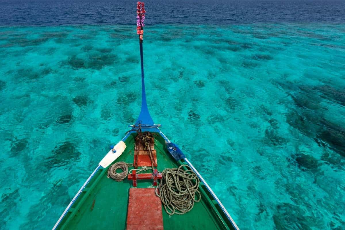 Aerial view of the front part of a traditional Maldivian boat, dhonis, above crystal clear blue water