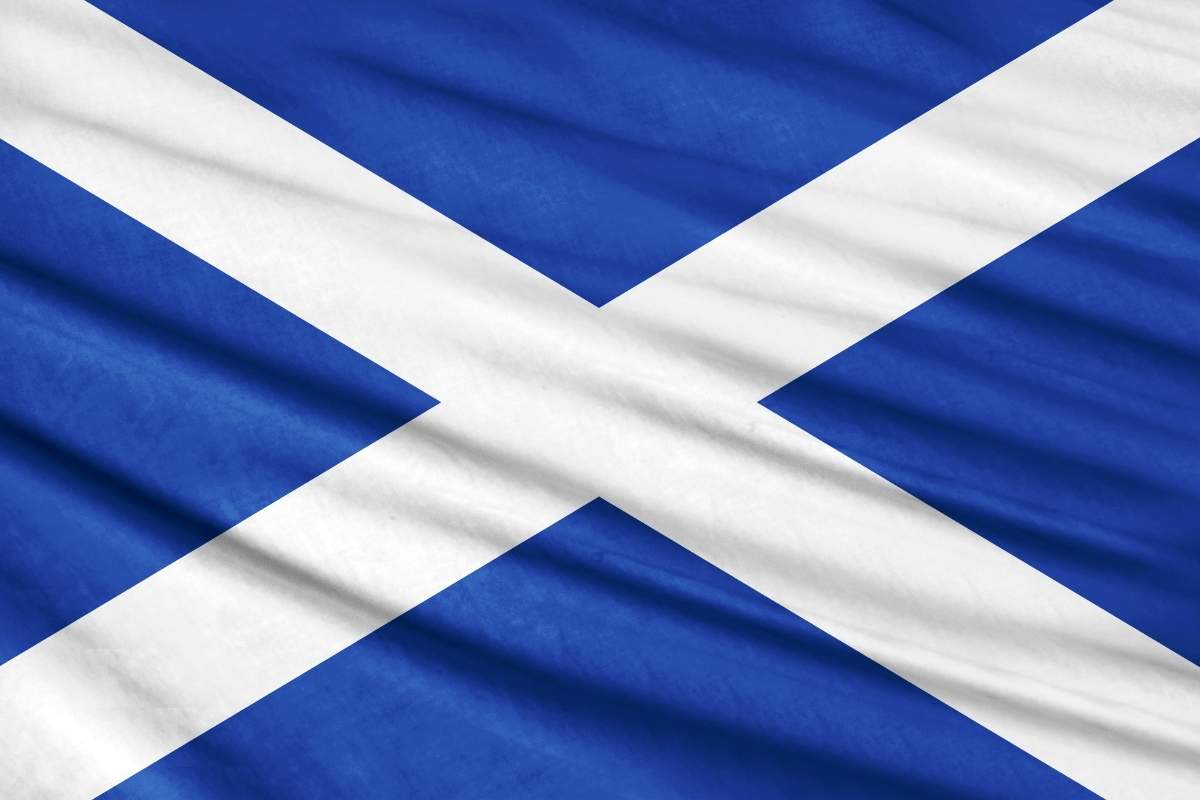 The flag of Scotland made up of a white X over a blue background displayed as if moving in the breeze
