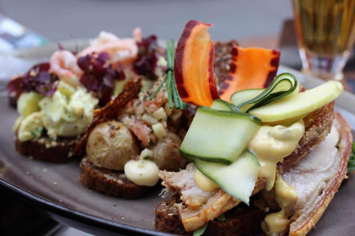 A selection of Smørrebrød; a Danish open faced sandwich with various toppings on top of a brown plate