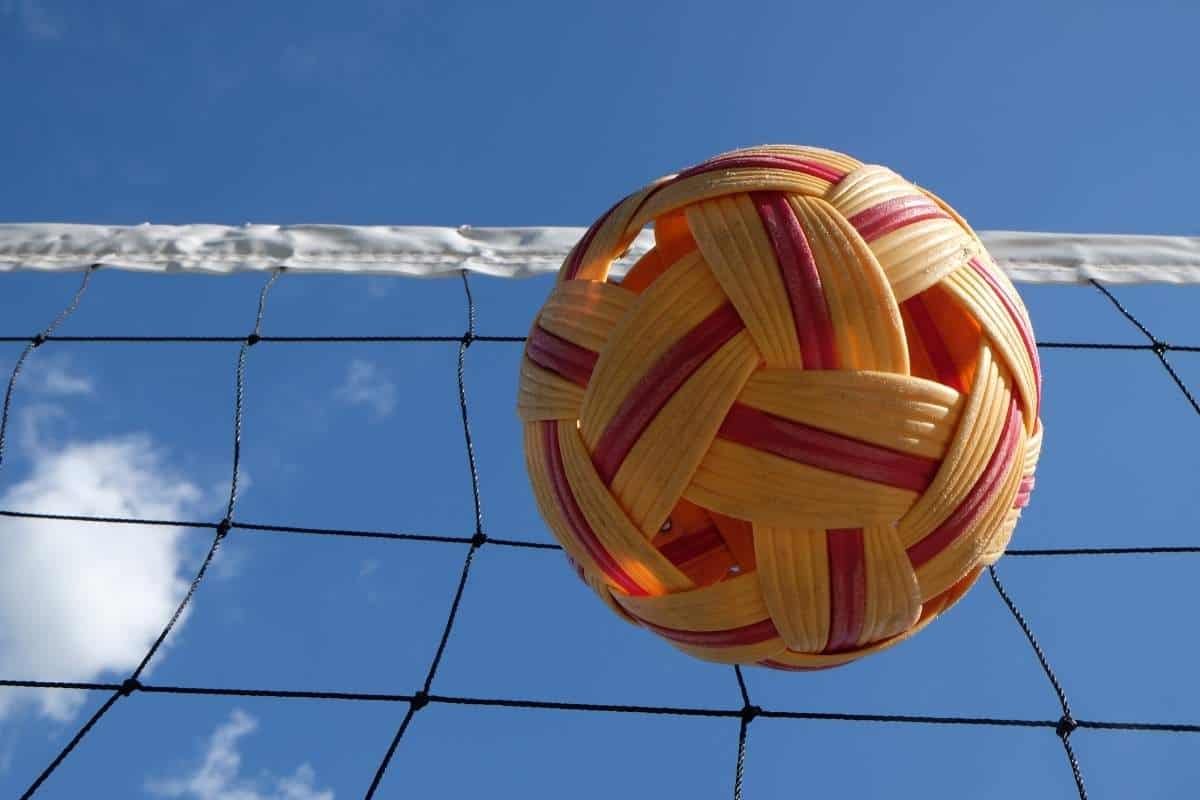 A woven ball used for the sport of sepak takraw in Vietnam in front of a long net with a blue sky behind it
