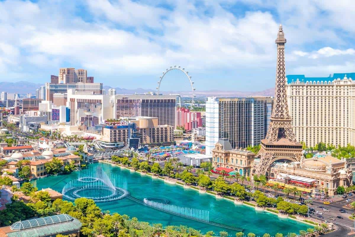 Las Vegas cityscape on a sunny day with views of the Bellagio fountain, Eiffel Tower replica, High Roller Ferris Wheel, and other resort buildings