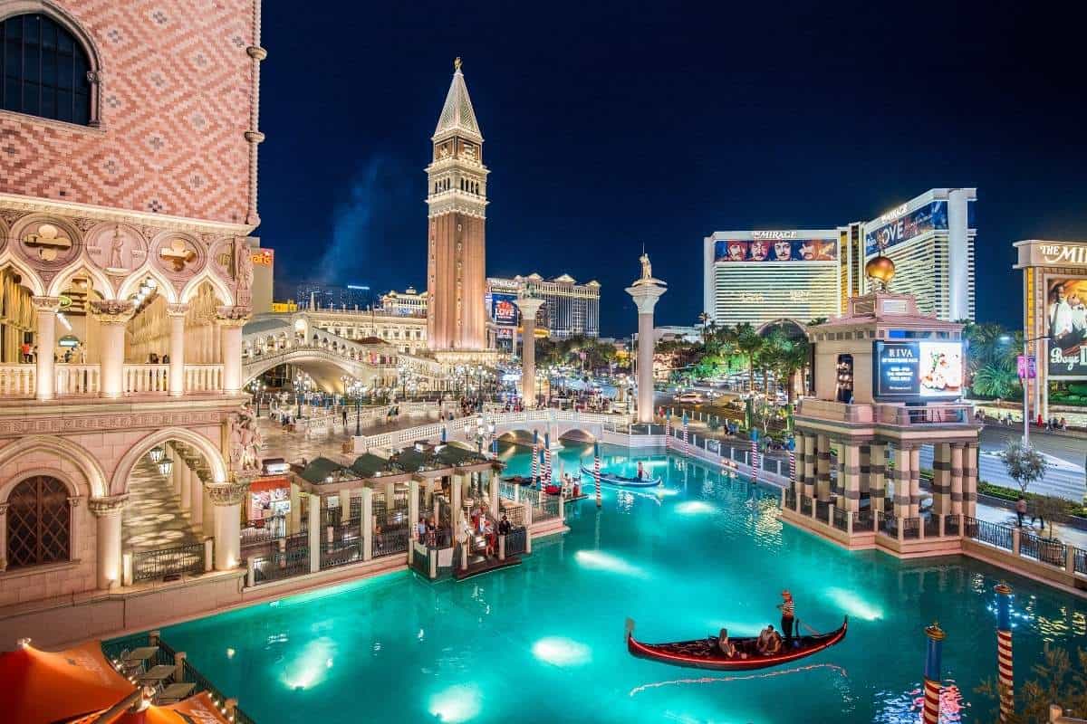 Las Vegas Strip with the Venetian Resort illuminated at night with a boat gliding on the man made lake in the foreground