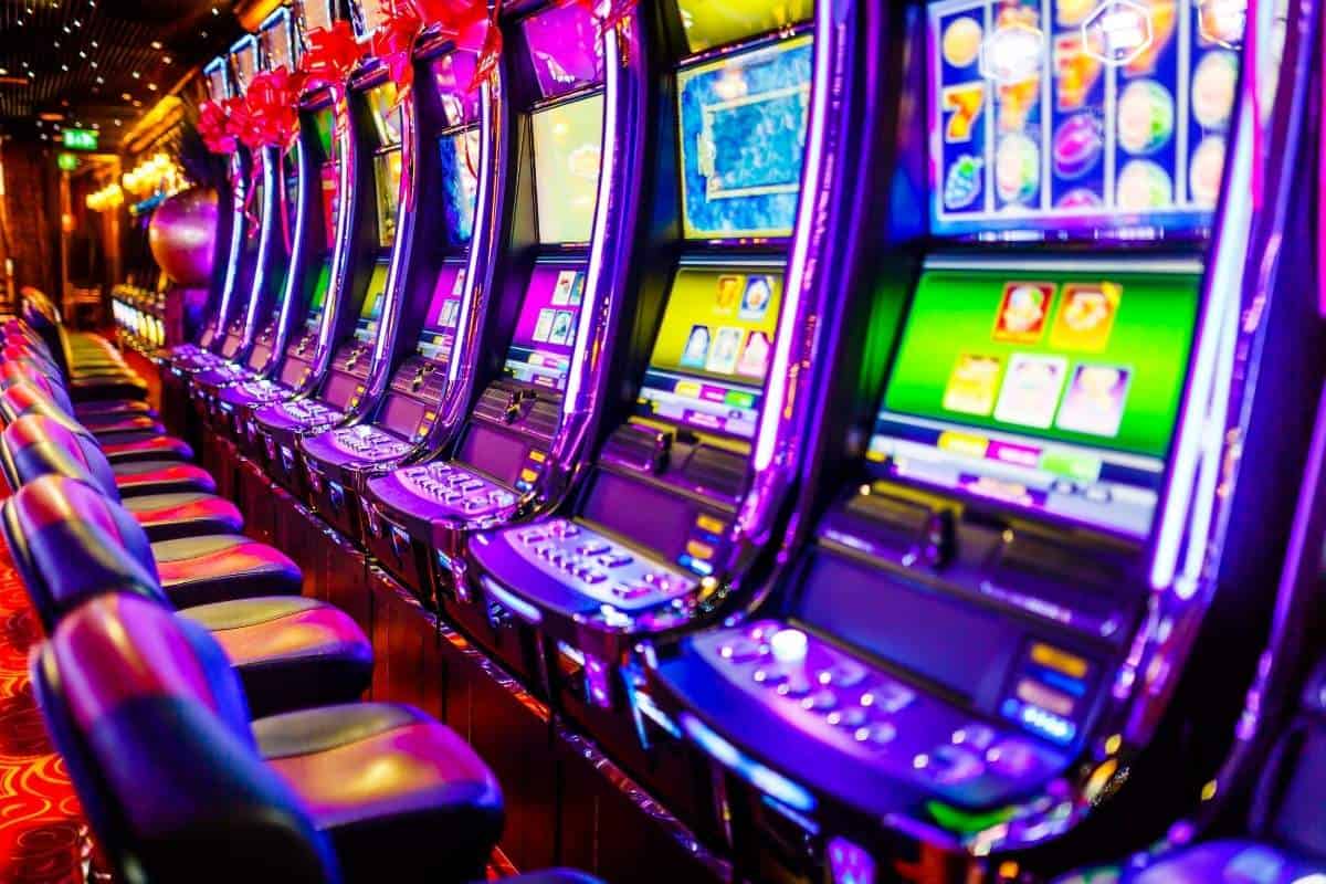 The bright lights of a line of empty electronic slot machines in a casino