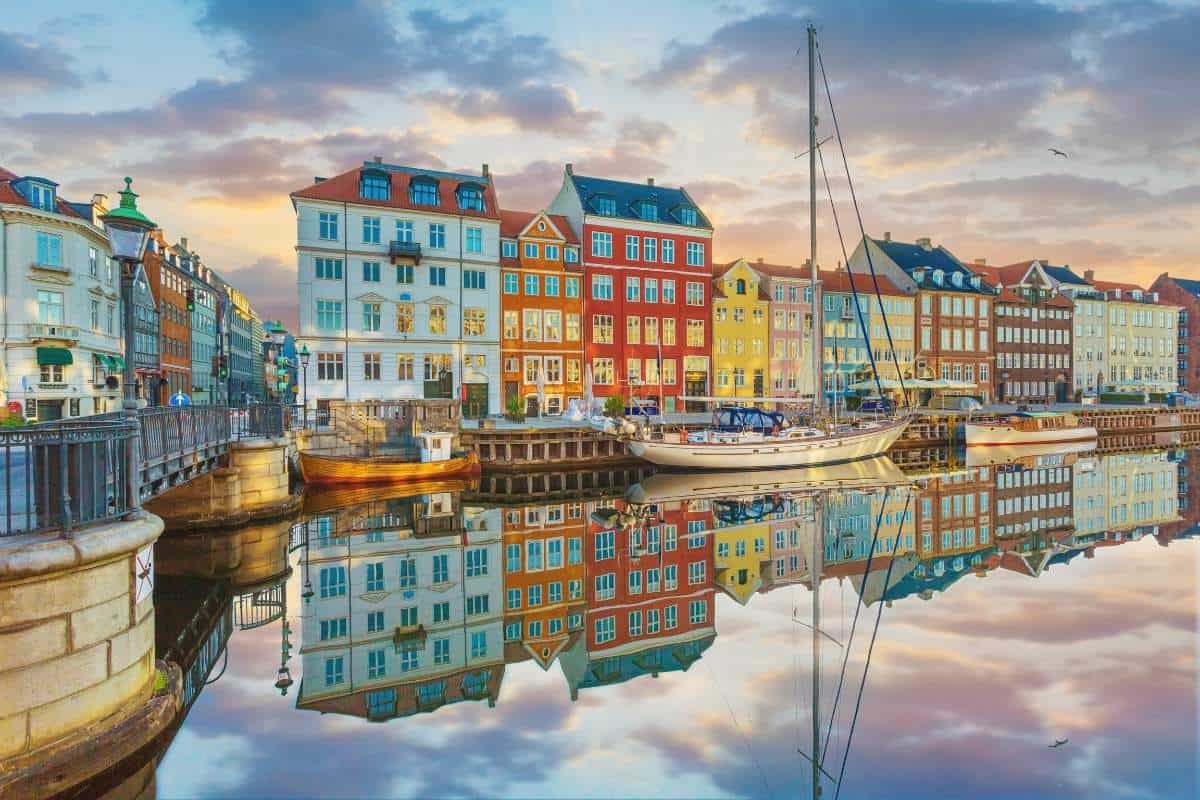 A beautiful sunset and a row of colorful houses reflected on the water in the harbour at Nyhavn in Denmark