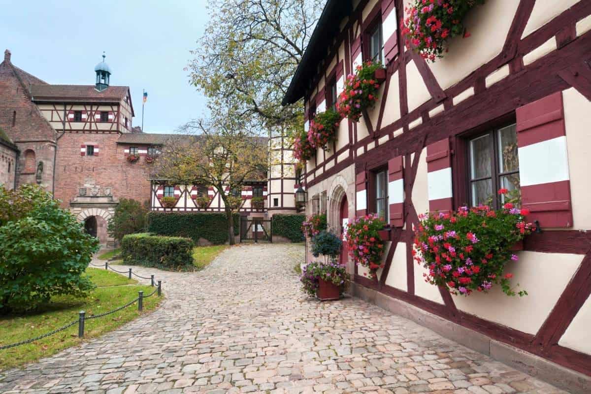 Cobblestone path and scenic buildings with flowers on the window sills at the grounds of Nuremberg Castle
