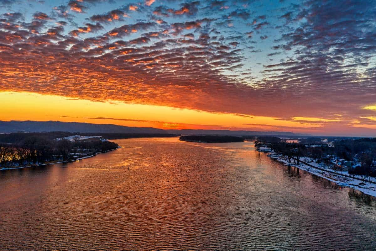 The Mississippi River glowing during a vibrant sunrise with oranges and yellows bursting amid the sky