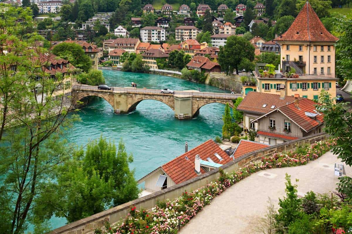 Cityscape of an old city with a brick bridge going over blue water surrounded by buildings with red roofs