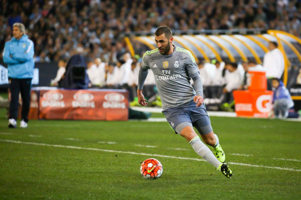 Soccer player on the field mid action with spectators in the stands watching