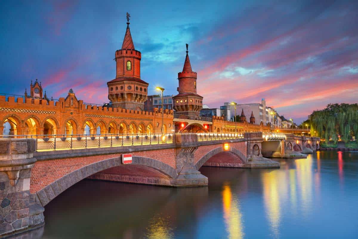 The famous Oberbaum bridge in Berlin, Germany during an impressive sunset with the lights of the bridge reflecting off the water