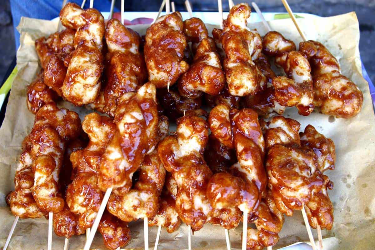 A pile of sticky fried rice balls on a stick with a sheet of parchment paper underneath