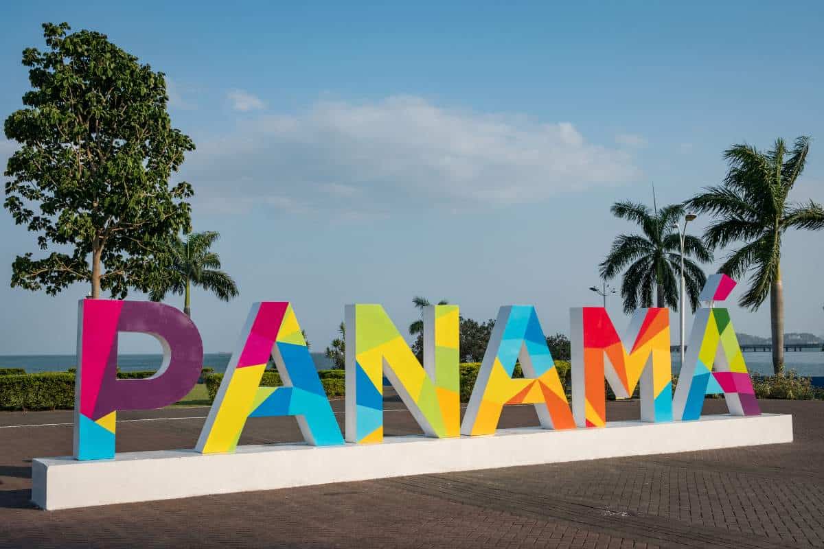 A brightly colored Panama sign in front of an ocean view with palm trees on either side