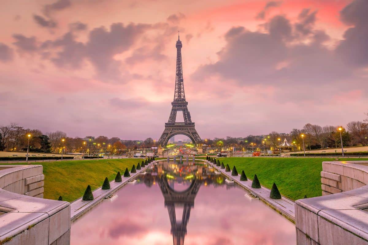Wide angle view of the Eiffel Tower in Paris, France with a reflection of the structure in the water in front of it 
