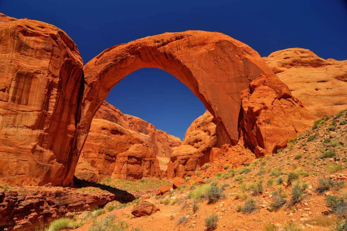 View of Rainbow Bridge National Monument in Utah showing the vibrant red rocks and deep blue sky in the background