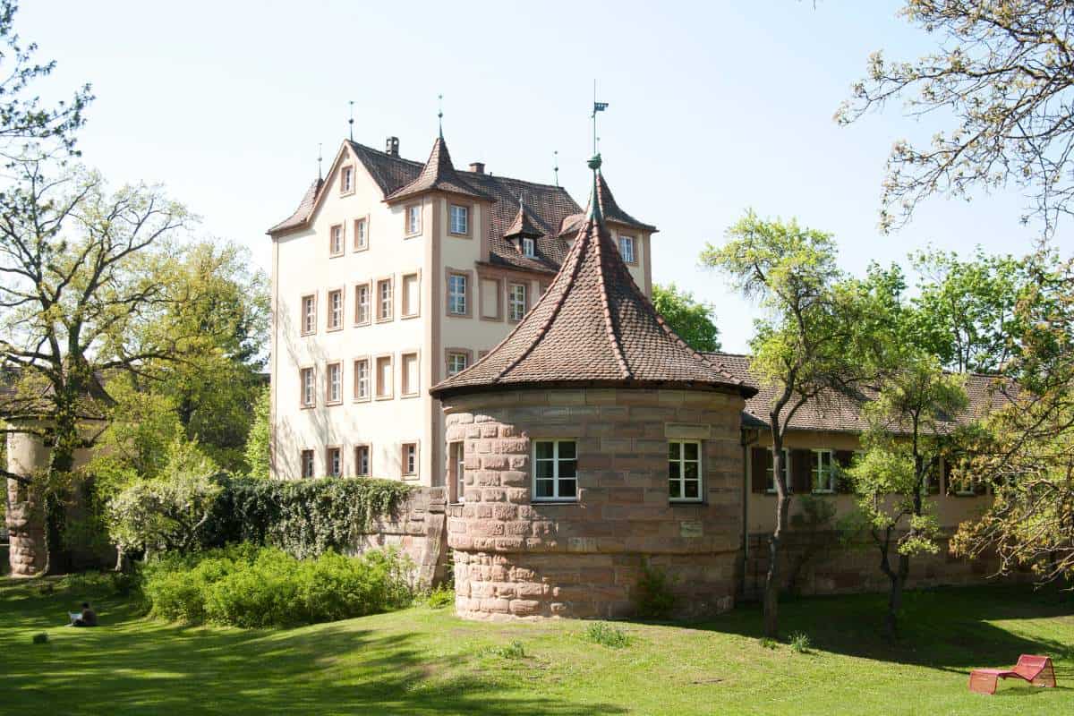 View of an old carriage house at a castle complex surrounded by lush greenery
